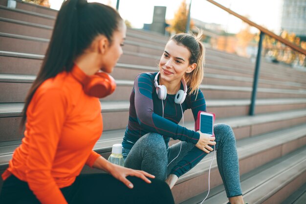 Two attractive female runner taking break after jogging outdoors