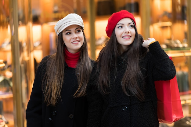두 매력적인 웃는 젊은 여성이 도시에서 쇼핑