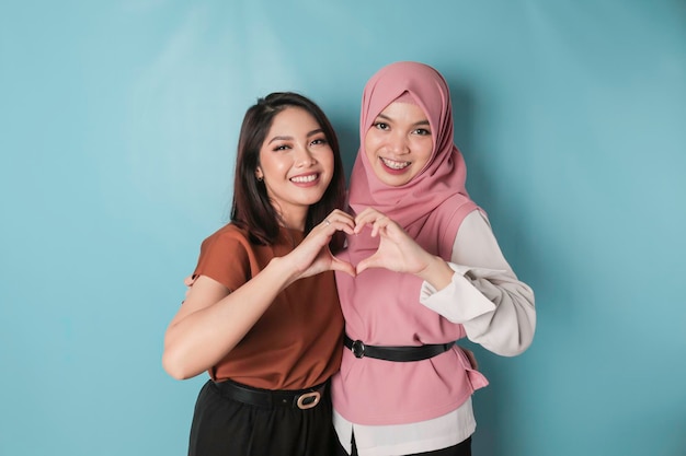 Two attractive young Asian women feels happy and a romantic shapes heart gesture expresses tender feelings and friendship concept