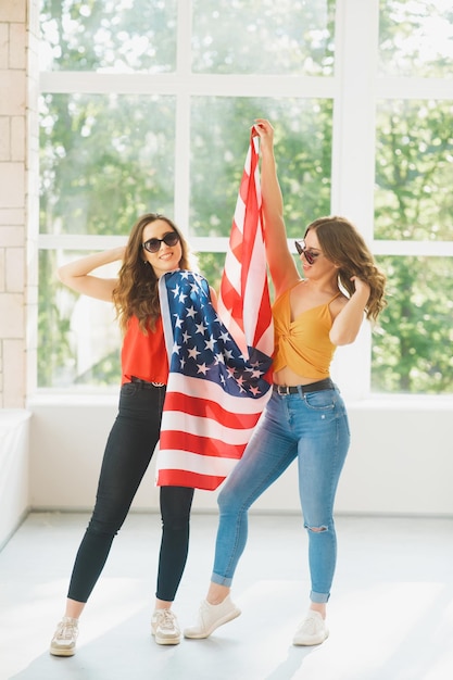 アメリカの国旗アメリカ独立記念日のお祝いとサングラスをかけた2人の魅力的な若い女の子