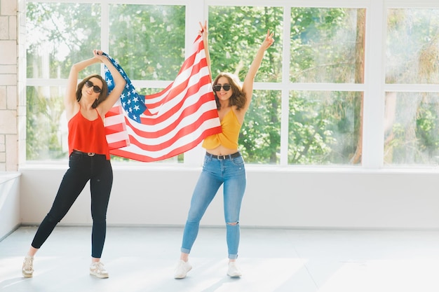 Two attractive young girls in sunglasses with the American flag USA independence day celebrations