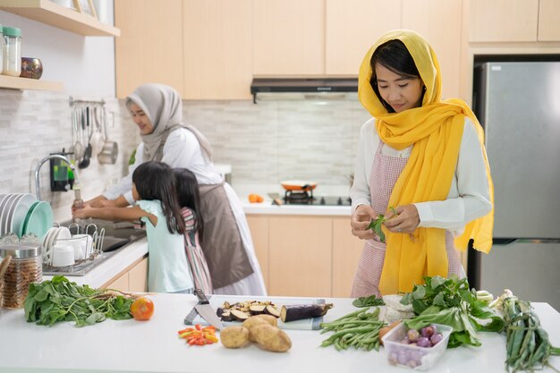 一緒にイフタールディナーを準備している2人の魅力的な若いイスラム教徒の女性。キッチンでラマダンとイードムバラク料理