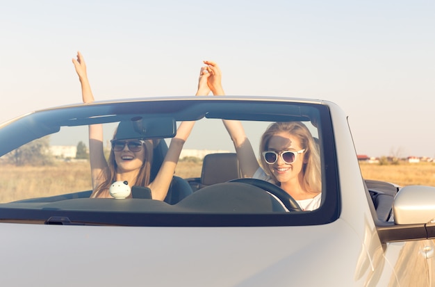 Two attractive young women in a cabriolet car