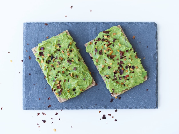 Two avocado toasts on a slate plate from above