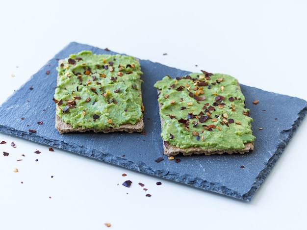 Two avocado toasts on a slate plate