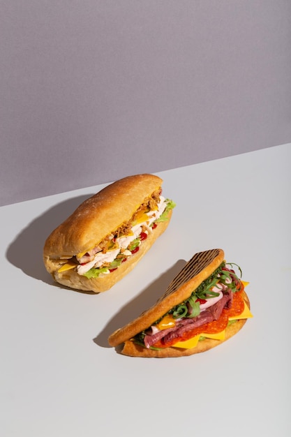 Two baguette sandwiches with chicken salami salad on grey hard shadow high quality photo