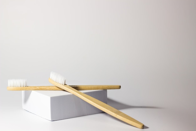 two bamboo toothbrushes on a platform or stand on a white background