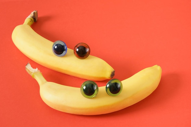 Two banana face with eyes cheerful faces made of plastic doll eyes and fresh yellow bananas