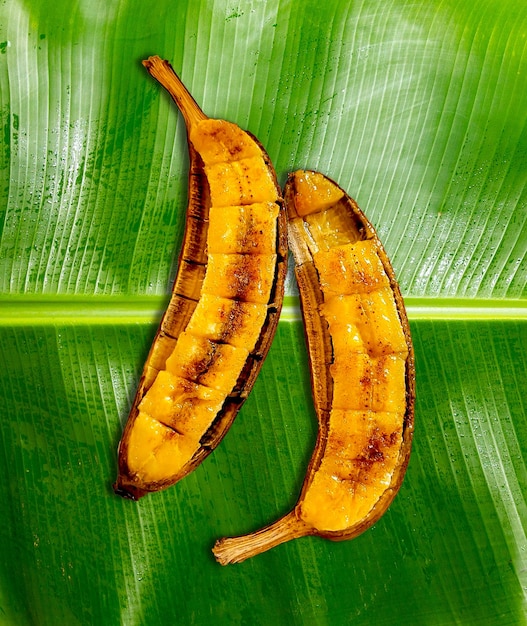 Photo two banana's are shown on a green leaf.