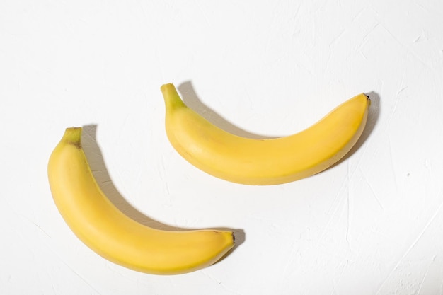 白い背景の上の 2 つのバナナ 皮が付いたままの天然バナナ全体