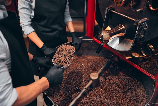 Photo two baristas enjoying burned beans aroma while holding them on spatula industry concept croped image