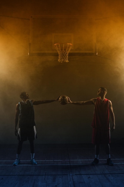 Photo two basketball player holding a single basketball