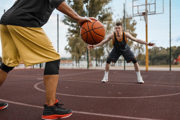 Two basketball players work out tactics on outdoor court.