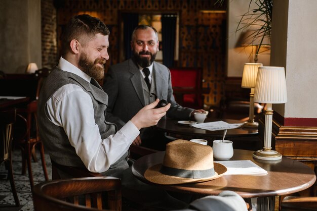 Two bearded men wearing old fashioned suits talking or discuss something in the restaurant