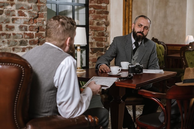 Two bearded men wearing old fashioned suits talking or discuss something in the restaurant