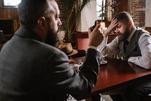 Two bearded men wearing old fashioned suits talking or discuss something in the restaurant