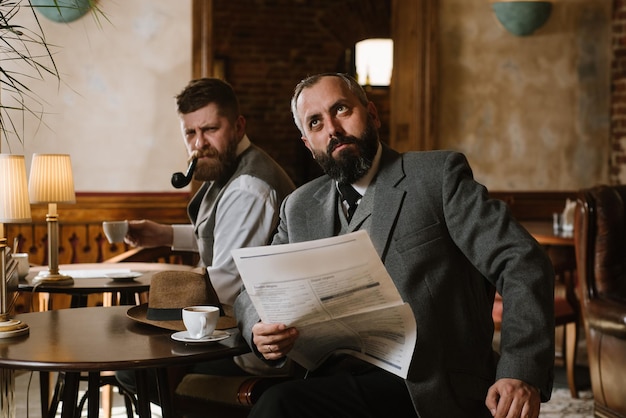 Two bearded men wearing old fashioned suits talking or discuss something in the restaurant