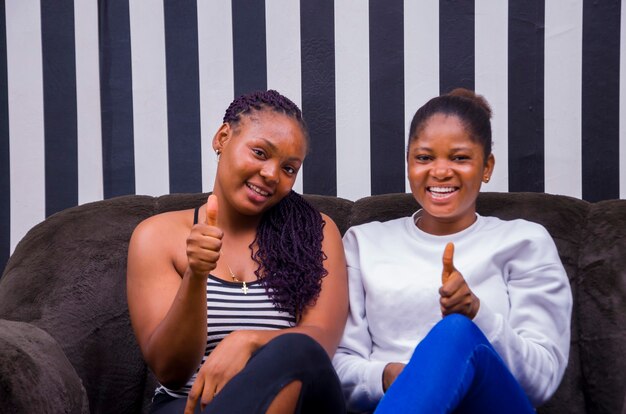 Two beautiful african ladies smiling as they did thumbs up