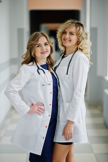 Photo two beautiful female doctors or medical workers in white coats posing in the hospital.