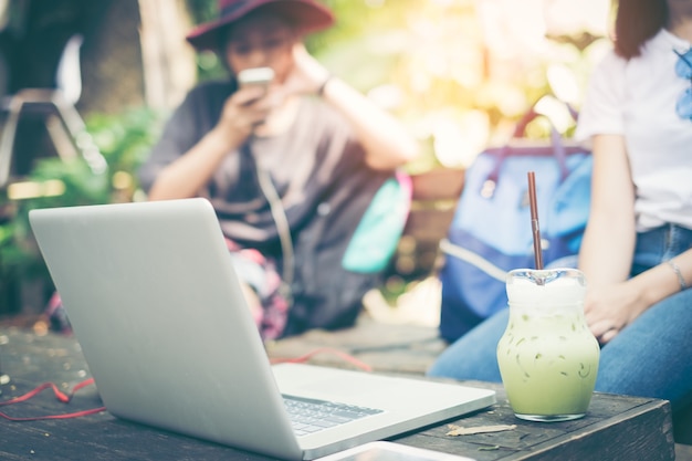 Two beautiful girls cups and laptop in summer cafe