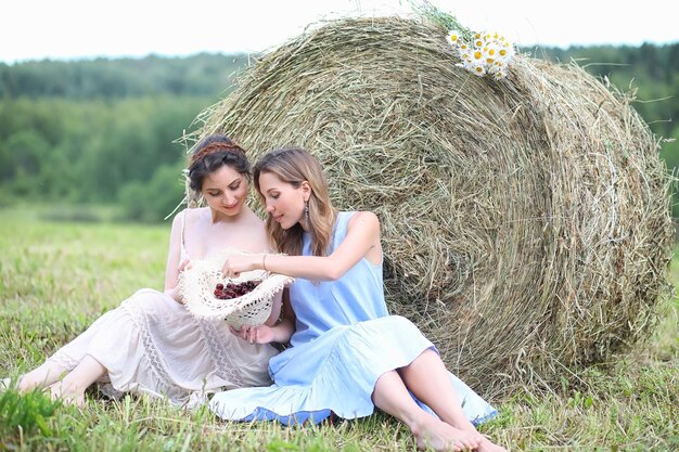 Две красивые девушки в платьях на летнем поле с ягодами