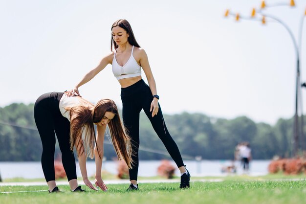 Foto due belle ragazze fanno esercizi all'aperto nel parco