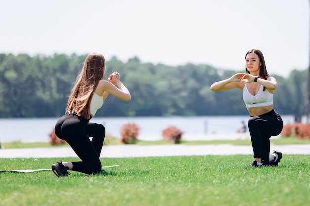 Foto due belle ragazze fanno esercizi all'aperto nel parco