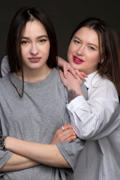 Two beautiful girls-friends on a dark background.