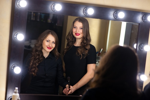 Two beautiful girls look in the mirror