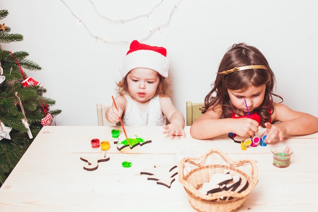 2人の美しい女の子が木製のクリスマスの置物を描いた