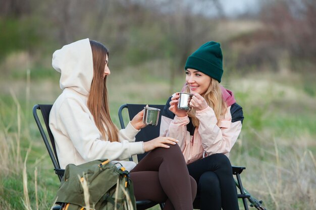 사진 두 명의 아름다운 소녀가 접이식 의자에 앉아 자연에서 차를 마시고 여행 여행자