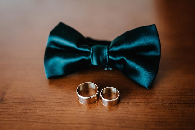 Two beautiful golden wedding rings bowtie groom on a light\
wooden background wedding accessories