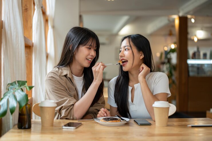 Photo 美しくて幸せな2人のアジア人女性がカフェで一緒にデザートを楽しんでいます