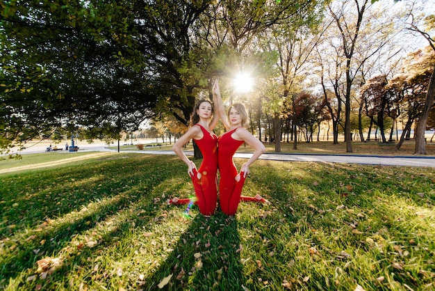 クローズアップで晴れた日に公園でヨガの練習をしている2人の美しい、幸せな若い女性