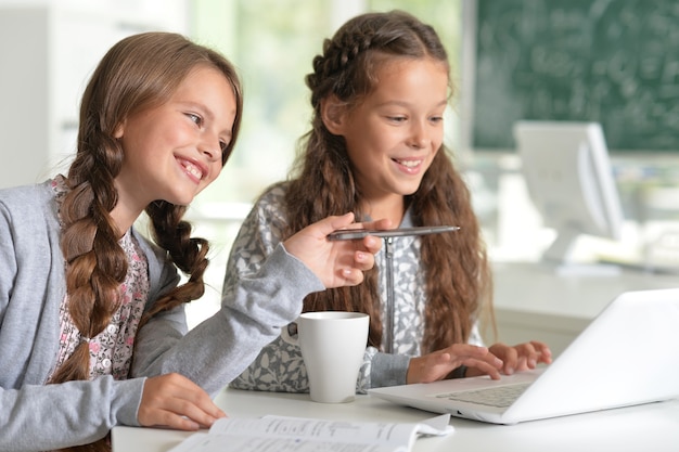 Two beautiful little girls at class with laptop