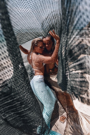 Premium Photo  Two beautiful mermaids with long tails caught in a fishing  net on the beach