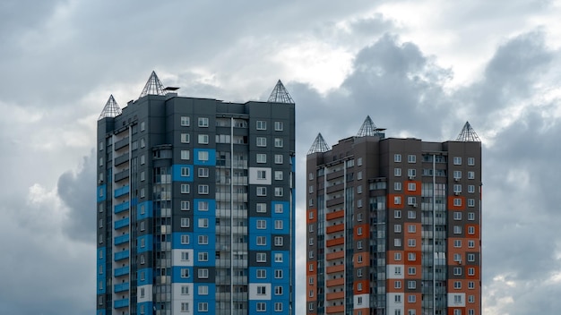 Two beautiful modern multistorey buildings on the background of gray rainy clouds Urban landscape Residential development