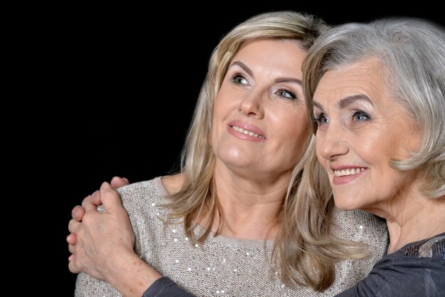 Two beautiful senior women posing against black background