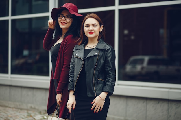 two beautiful and stylish girlfriends walking around the city with packages and shopping