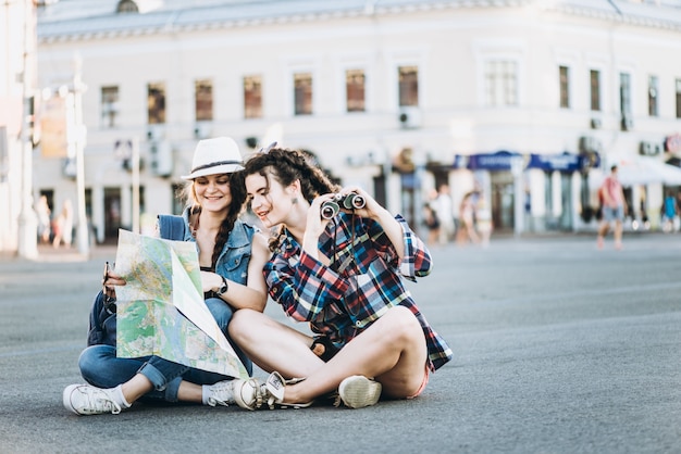 Photo two beautiful tourist girls with a map walk around the old city