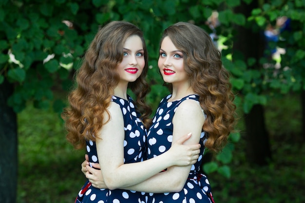 Two beautiful twins in spotted dresses