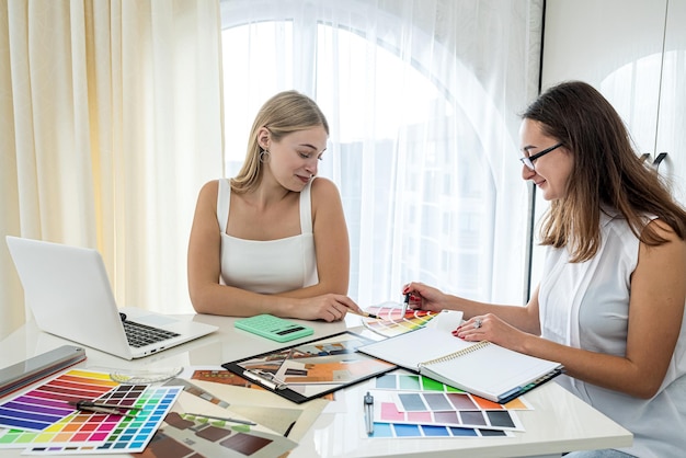 Two beautiful women designers working on new designs of new rooms at the table Design concept