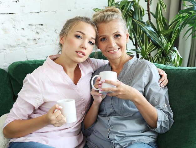 Photo two beautiful women mother and daughter drink coffee tea relationships and shared time