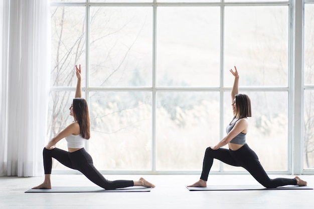 Two beautiful women performing yoga in a modern studio