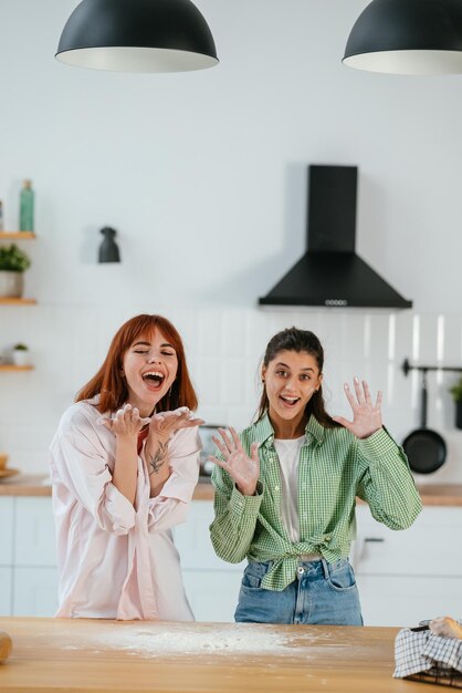 Foto due belle donne giocano con la farina in cucina