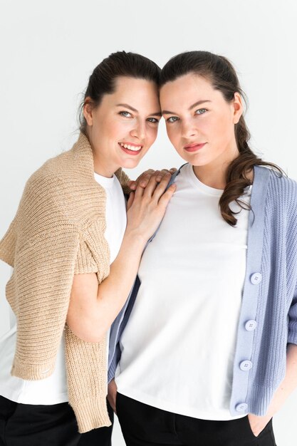 Two beautiful women twin sisters posing white background having fun together