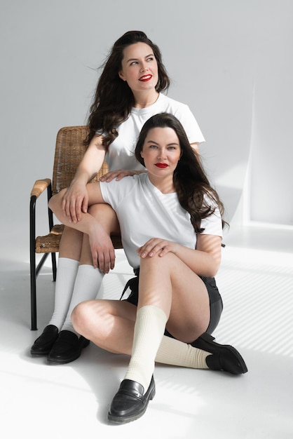 Two beautiful women twin sisters posing white background