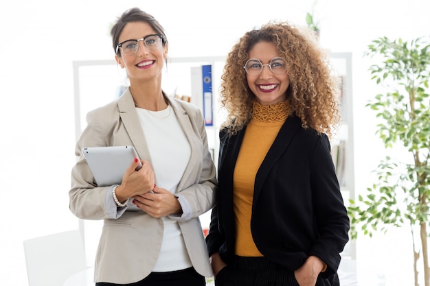 Two beautiful young businesswoman posing in the office.