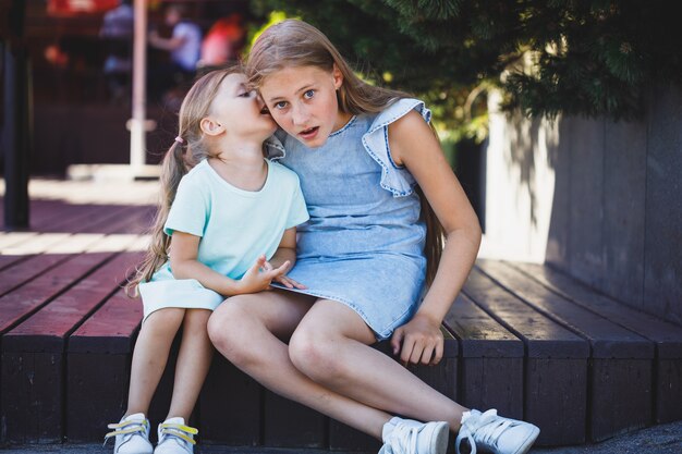 Two beautiful young girls are sitting on the veranda and are secret