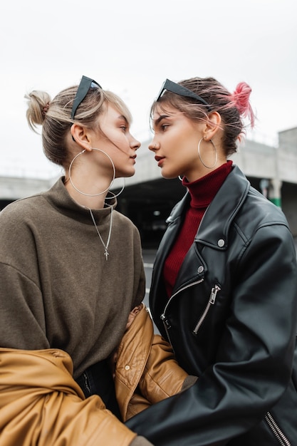 Two beautiful young lesbian girls in fashionable clothes with leather jacket on the street